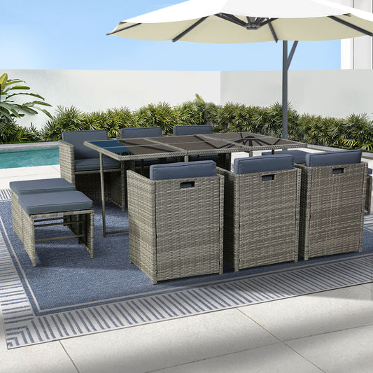 Outdoor patio furniture set with table, chairs, and ottomans on a patio with a pool and umbrella in the background.