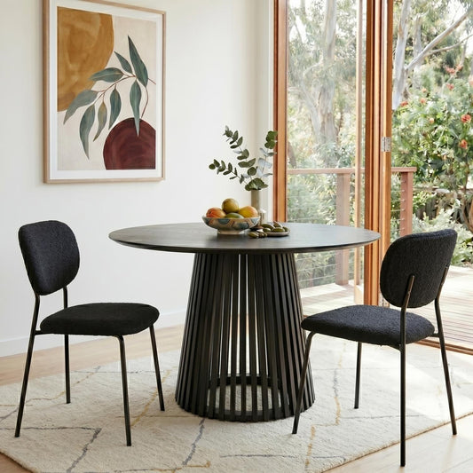 Modern black dining table with two chairs in a bright room with large windows.