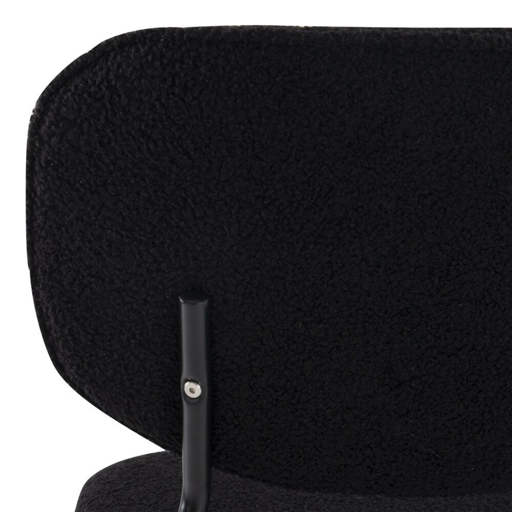 Close-up of a black dining chair with a textured backrest.