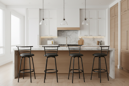 A modern kitchen island with a light wood base and white marble countertop, surrounded by four black metal bar stools with dark seats. The background features white and light wood cabinetry, marble backsplash, and three hanging pendant lights.