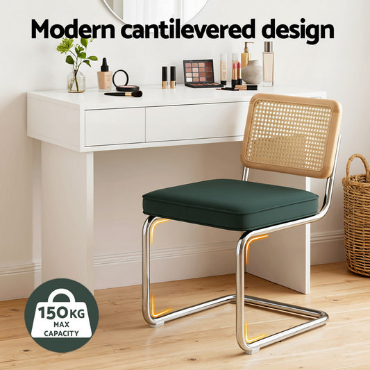 Modern cantilevered chair with green cushion in front of a white vanity table.