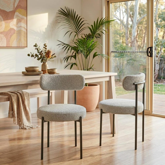 Dining area with a table, chairs, and plants in a bright room.
