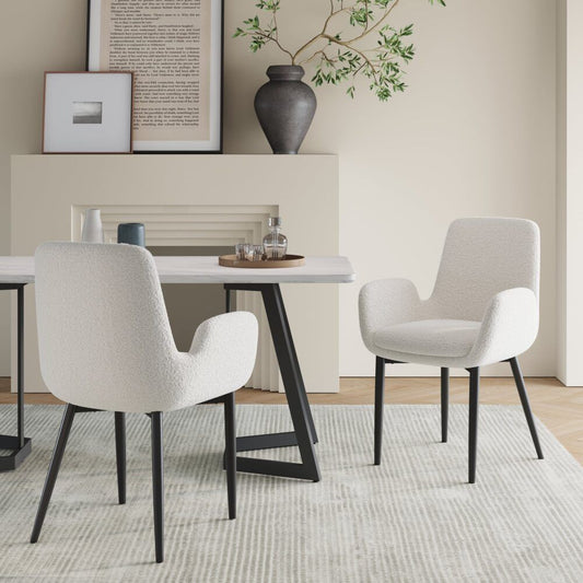 Dining room with a white table and chairs, framed pictures on the wall, and a vase.