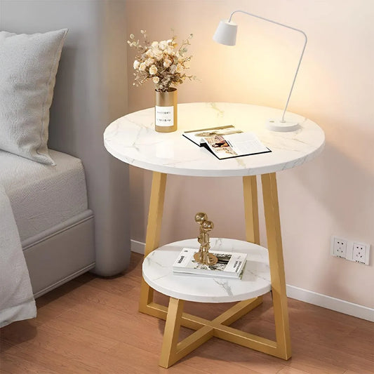 Round marble side table with wooden legs in a bedroom setting.