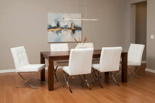 A modern dining room setup featuring a dark wood rectangular table surrounded by six white leather chairs with chrome legs, set against a warm gray wall with a framed abstract painting.